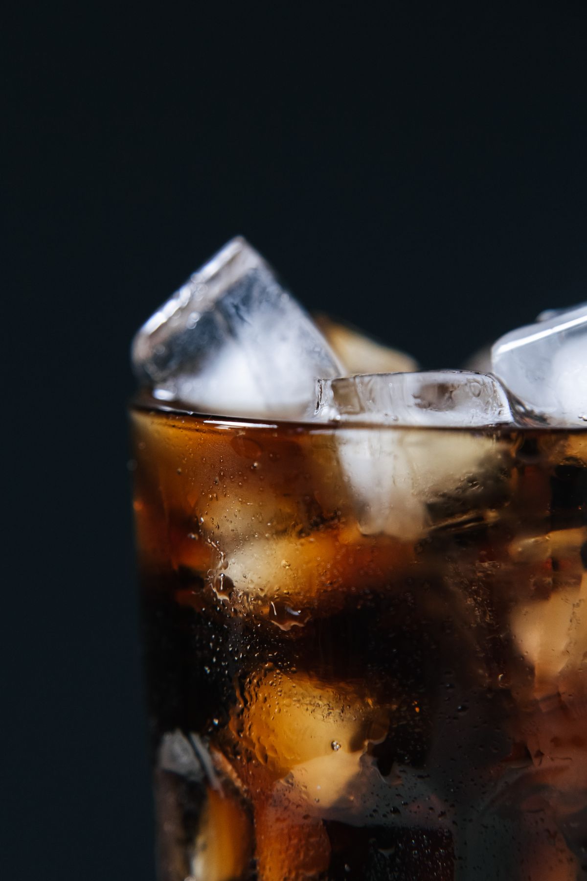 Close-up of a cold carbonated drink with ice cubes in a glass
