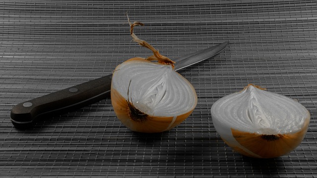 A halved onion with a knife on a cutting board